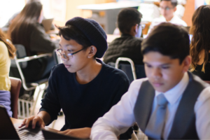 Two young people working on computers in a classroom